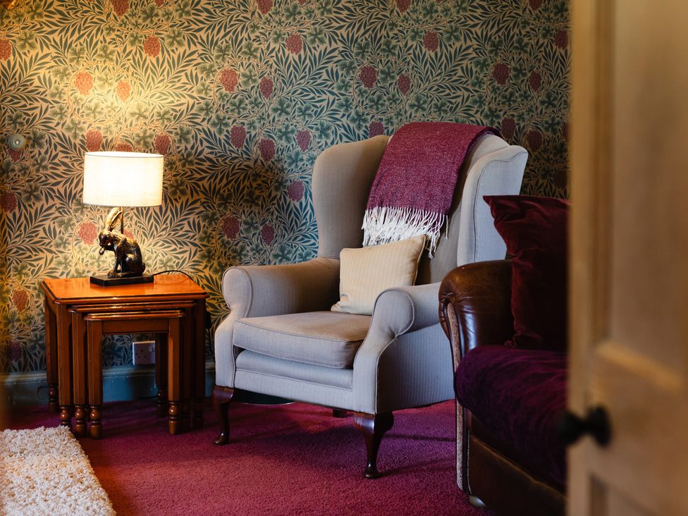 A living room with an armchair and table at Cheviot Manor in Akeld near Wooler