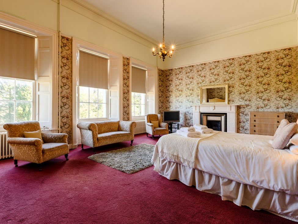 A bedroom with a bed, sofa, and fireplace at Cheviot Manor Akeld near Wooler