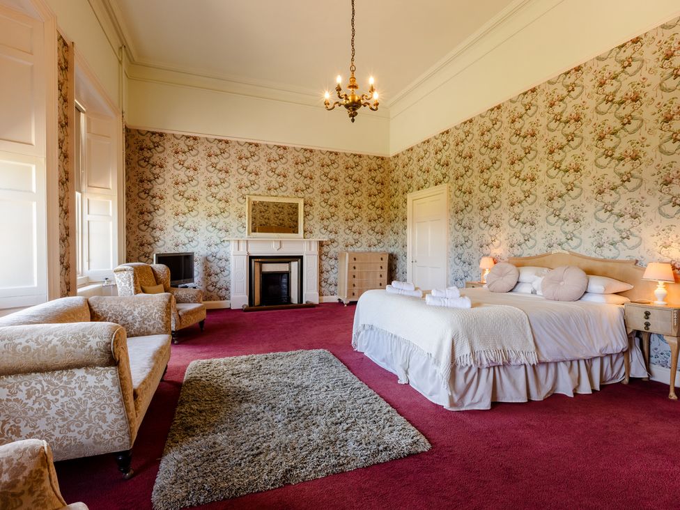 A bedroom with a bed and armchairs at Cheviot Manor in Akeld near Wooler