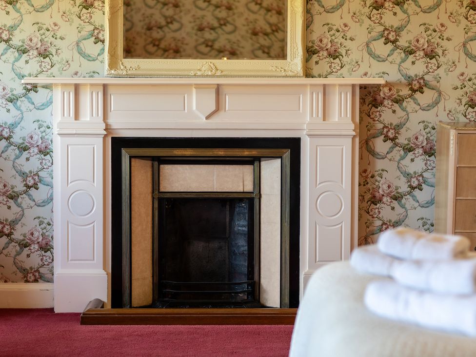 A fireplace with a mirror above in a bedroom at Cheviot Manor near Wooler