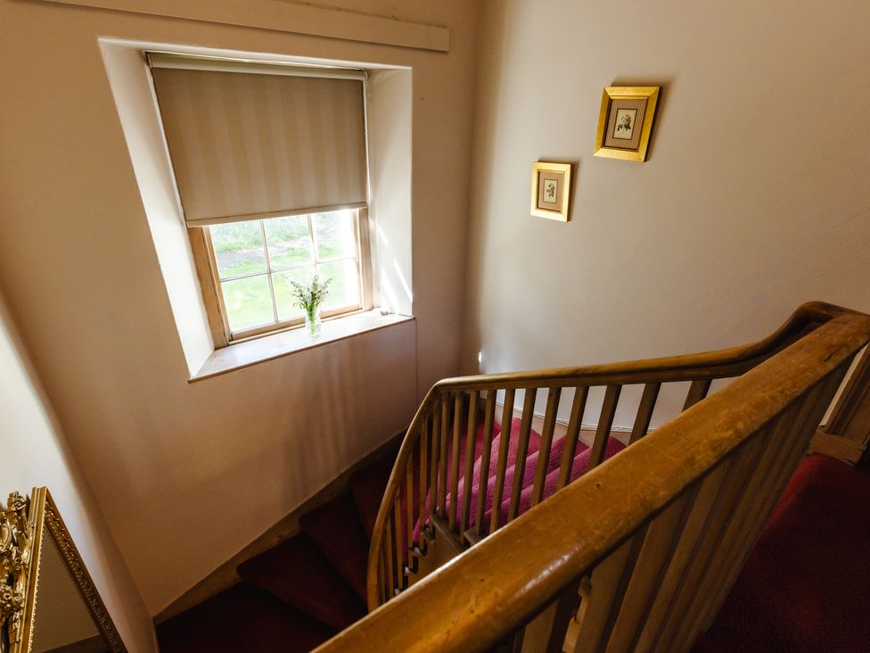 A staircase with a window and framed pictures at Cheviot Manor in Akeld near Wooler