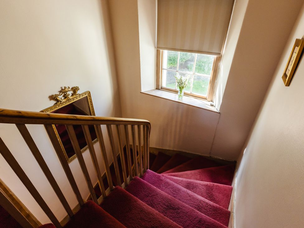 A staircase with a window and a mirror at Cheviot Manor in Akeld near Wooler