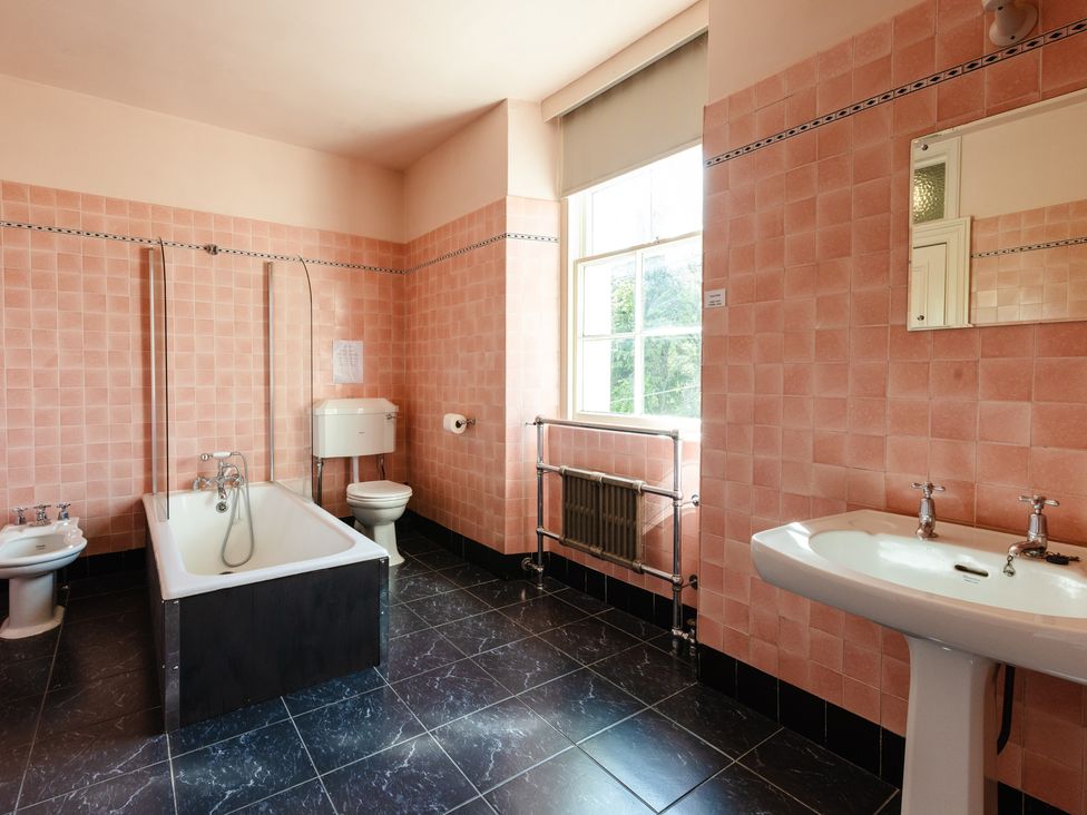 A bathroom with a bathtub, toilet, sink and window at Cheviot Manor Akeld near Wooler