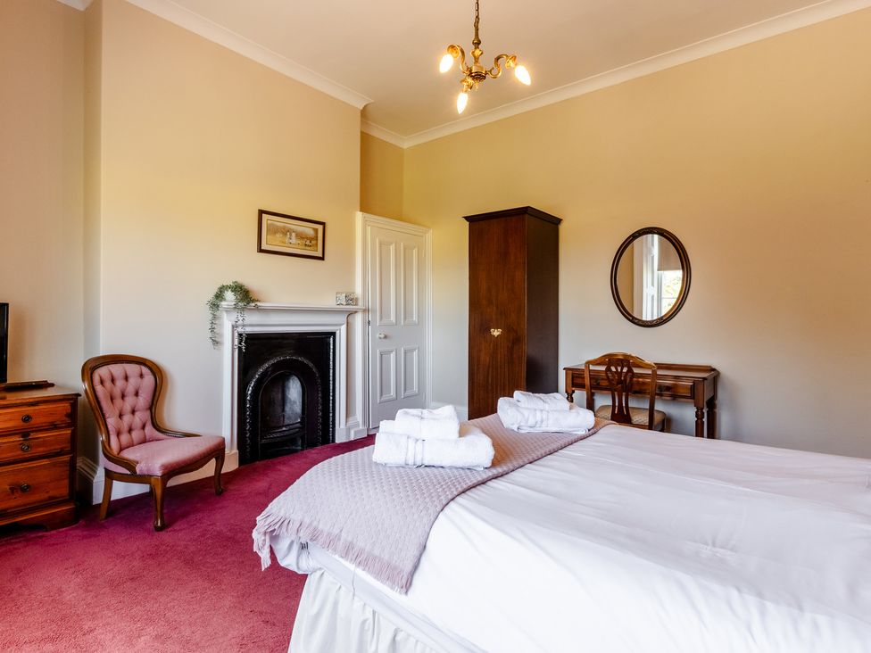 A bedroom with a bed and chair at Cheviot Manor Akeld near Wooler