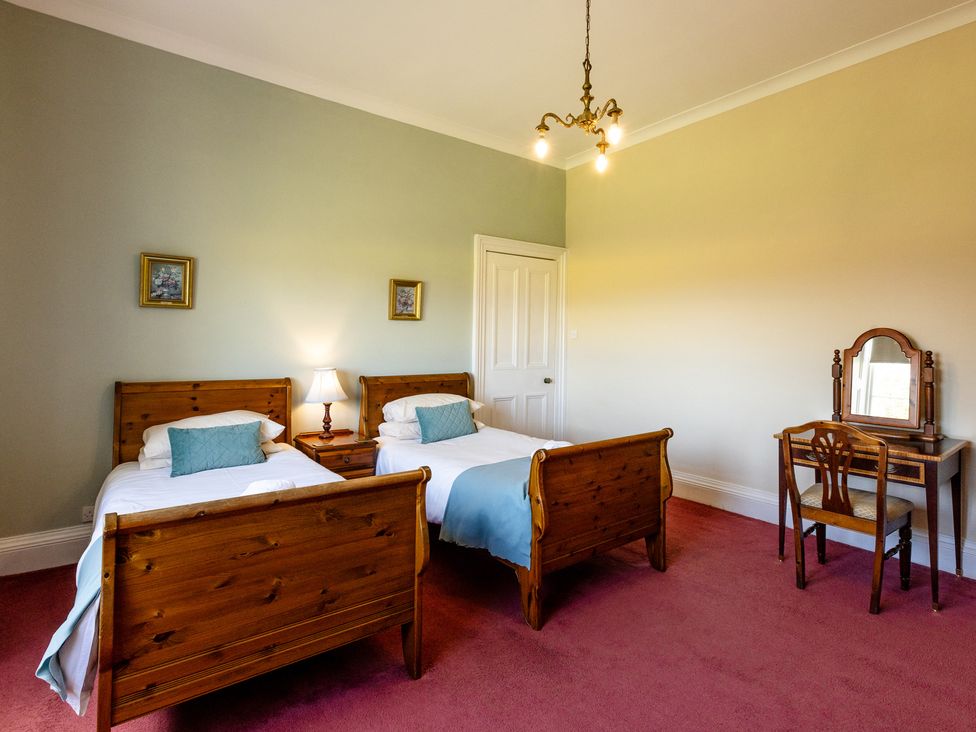 A bedroom with two beds and a dressing table at Cheviot Manor Akeld near Wooler