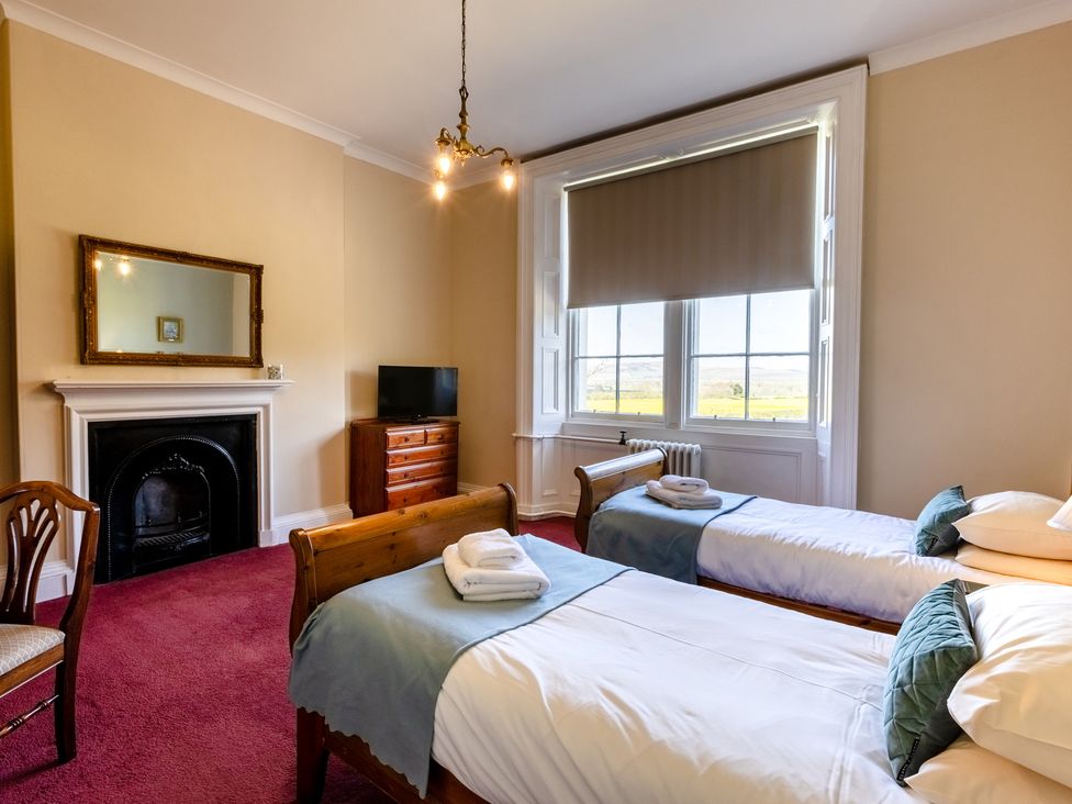 A bedroom with two beds and a television at Cheviot Manor Akeld near Wooler