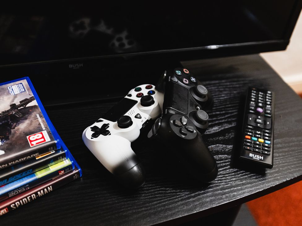 A living room with video game controllers and games at Cheviot Manor Akeld near Wooler