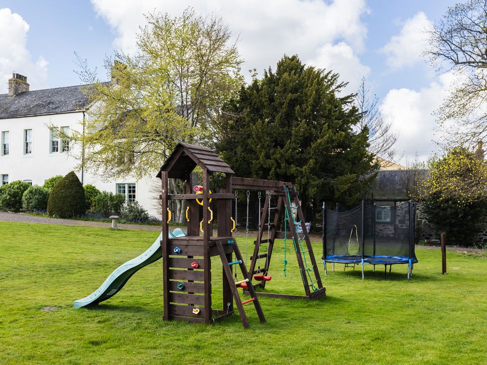 A playground with a slide and swings in the garden at Cheviot Manor near Wooler