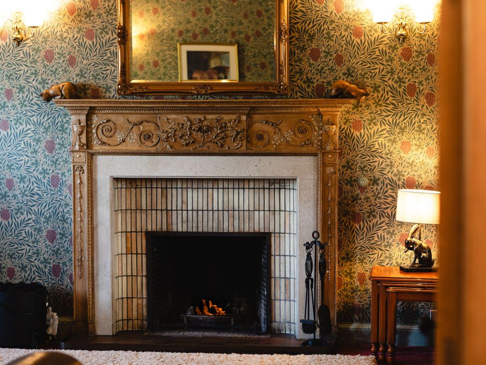 A sitting room with a fireplace and decorative wall at Cheviot Manor Akeld near Wooler
