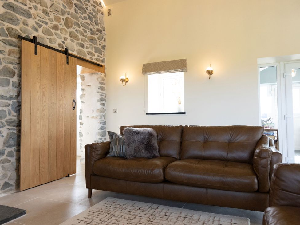 A living room with a sofa and stone wall at Golygfa Cwrt in Talybont