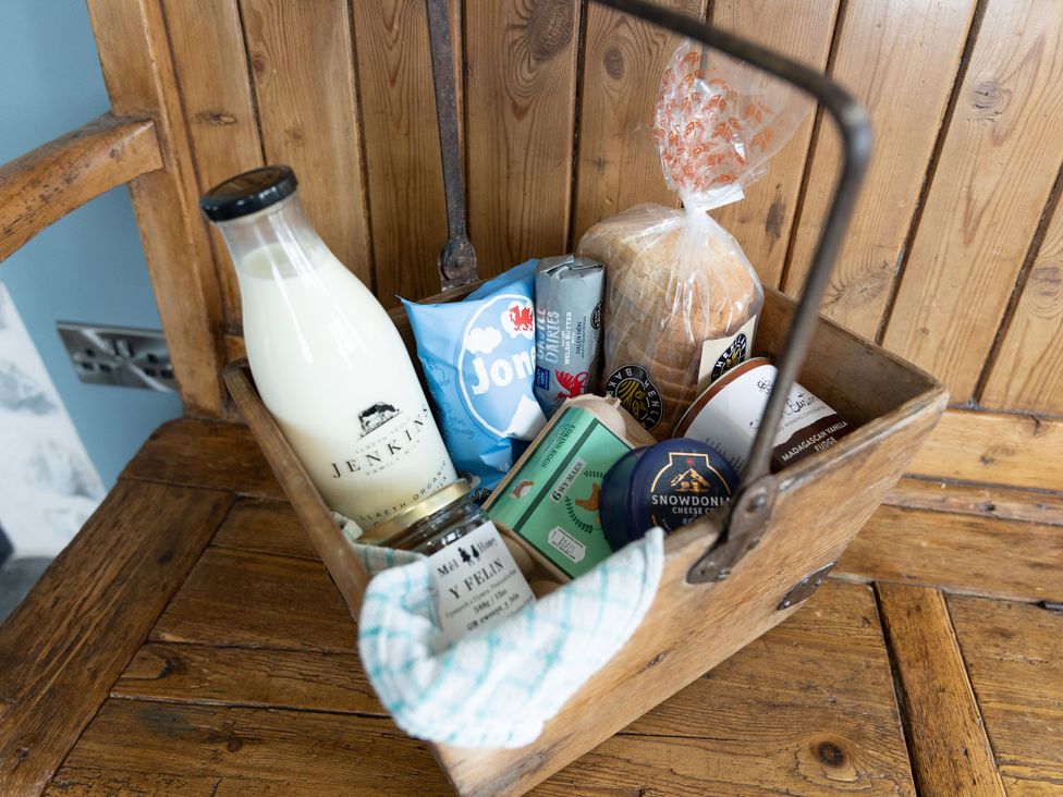 A basket containing milk, biscuits, bread, cheese, and yogurt at Golygfa Cwrt in Talybont