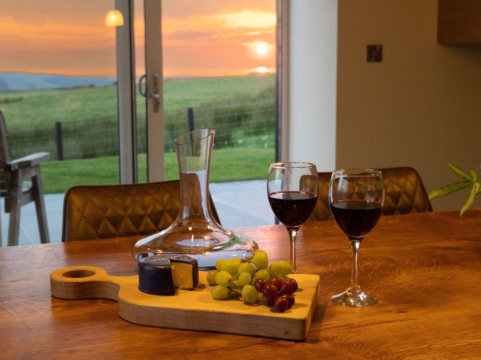 A dining room with wine glasses and cheese on a wooden board at Golygfa Cwrt in Talybont