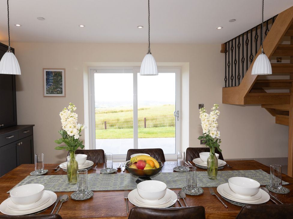 A dining room with a table set for meals and a view at Golygfa Cwrt Talybont