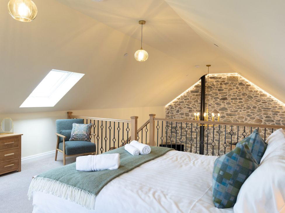 A bedroom with a bed and chair at Golygfa Cwrt in Talybont