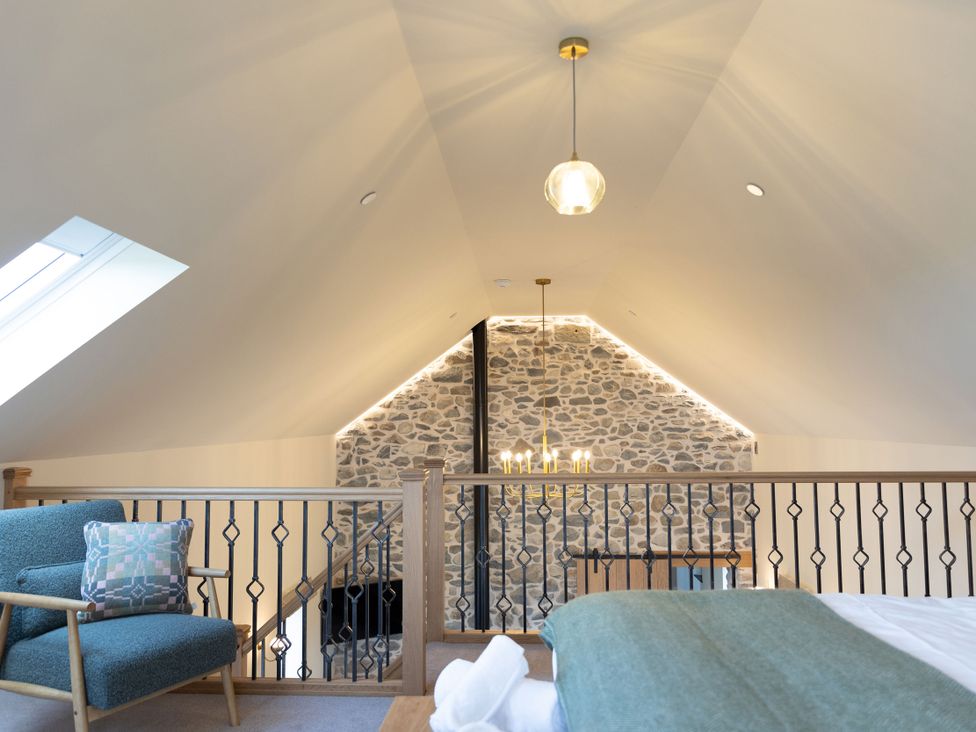 A loft with a stone wall and seating area at Golygfa Cwrt in Talybont