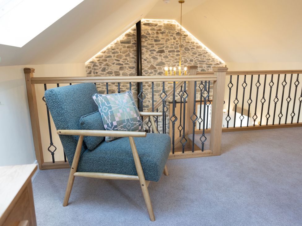 A loft with an armchair and a stone wall at Golygfa Cwrt in Talybont