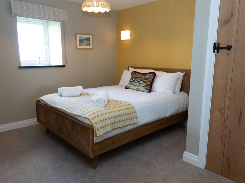A bedroom with a bed, window, and light fixture at Golygfa Cwrt in Talybont