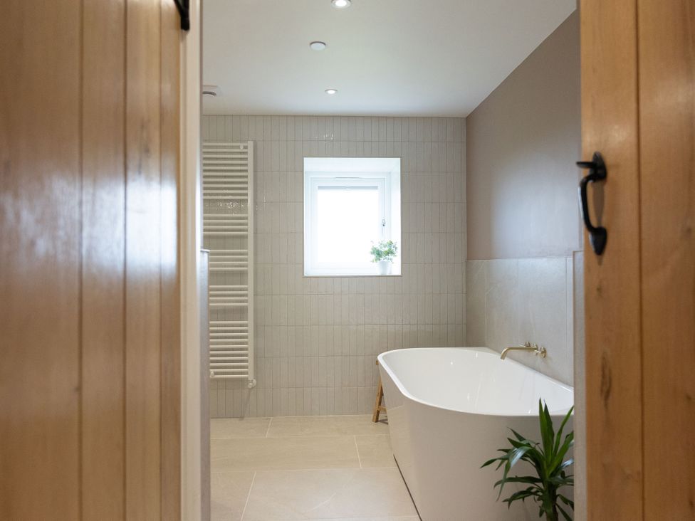 A bathroom with a bathtub, a radiator and a plant at Golygfa Cwrt, Talybont