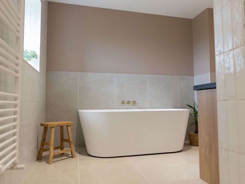 A bathroom with a bathtub and a stool at Golygfa Cwrt in Talybont