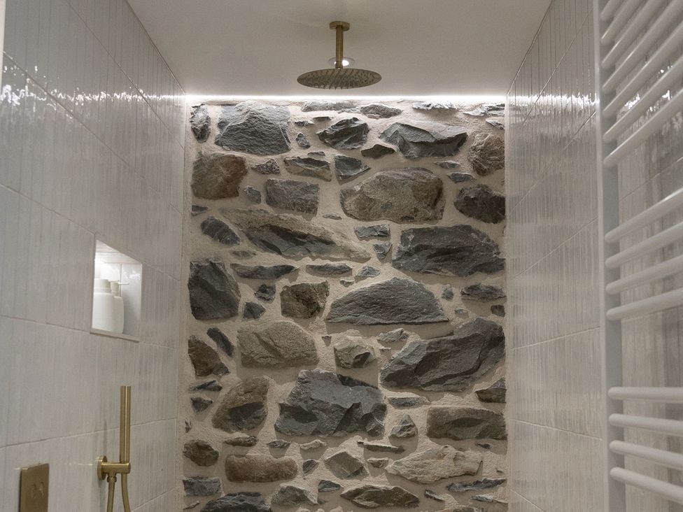 A bathroom featuring a stone wall and shower at Golygfa Cwrt Talybont