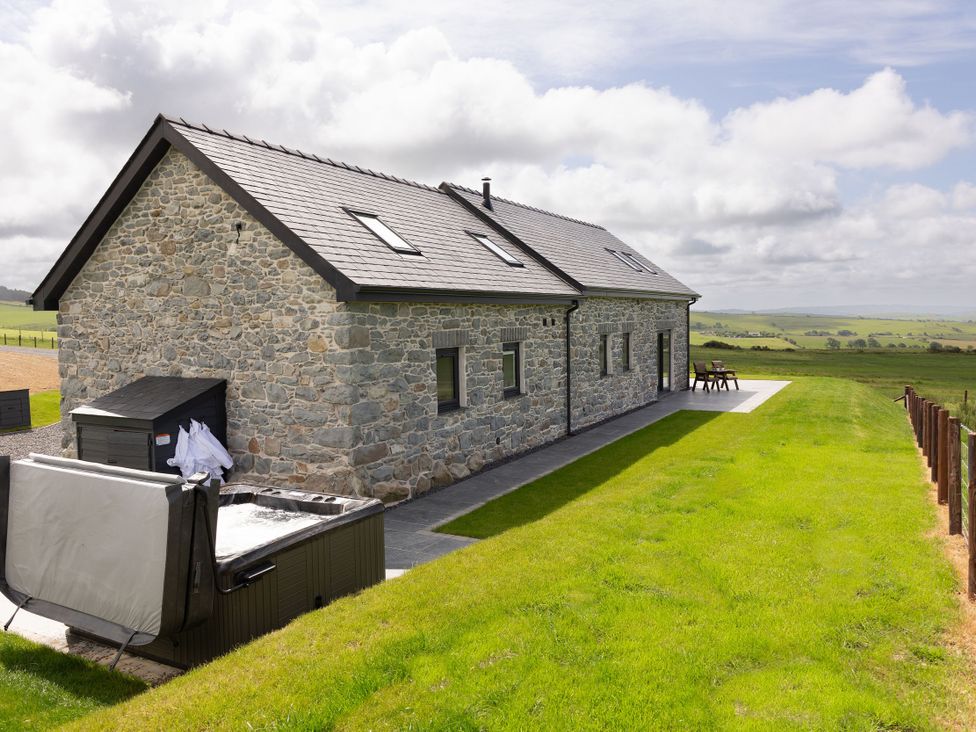 A stone house with a hot tub and patio seating at Golygfa Cwrt Talybont