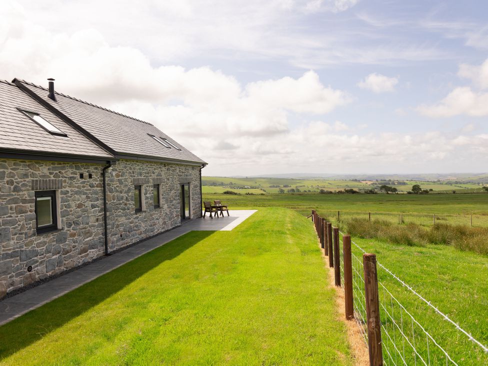 An outdoor area with a stone house and patio furniture at Golygfa Cwrt in Talybont