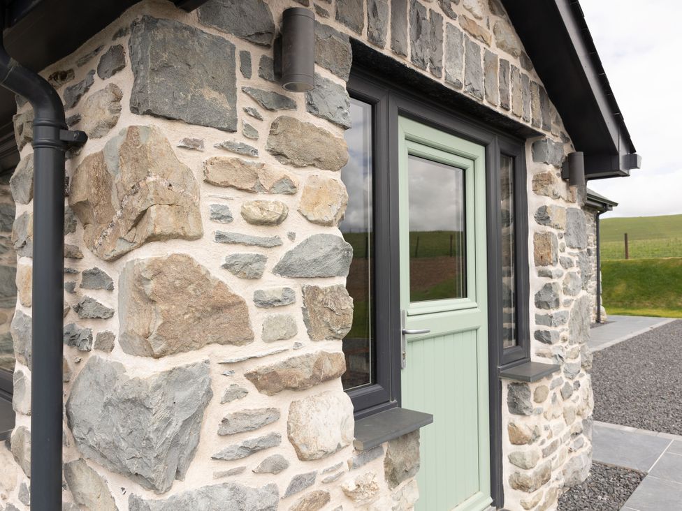 A stone wall with a green door and window at Golygfa Cwrt Talybont