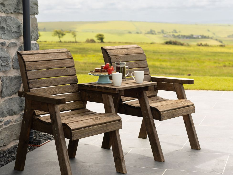 An outdoor seating area with wooden chairs and table at Golygfa Cwrt near Bontgoch and Penrhyncoch