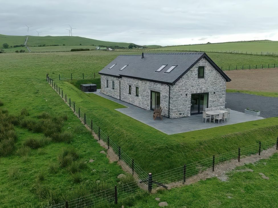 A house with a patio and hot tub near green fields at Golygfa Cwrt near Bontgoch and Penrhyncoch