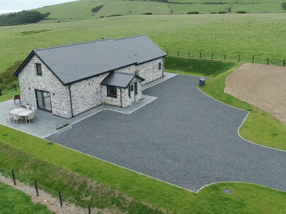 An outdoor view of a house with a patio and parking area near Golygfa Cwrt Near Bontgoch and Penrhyncoch