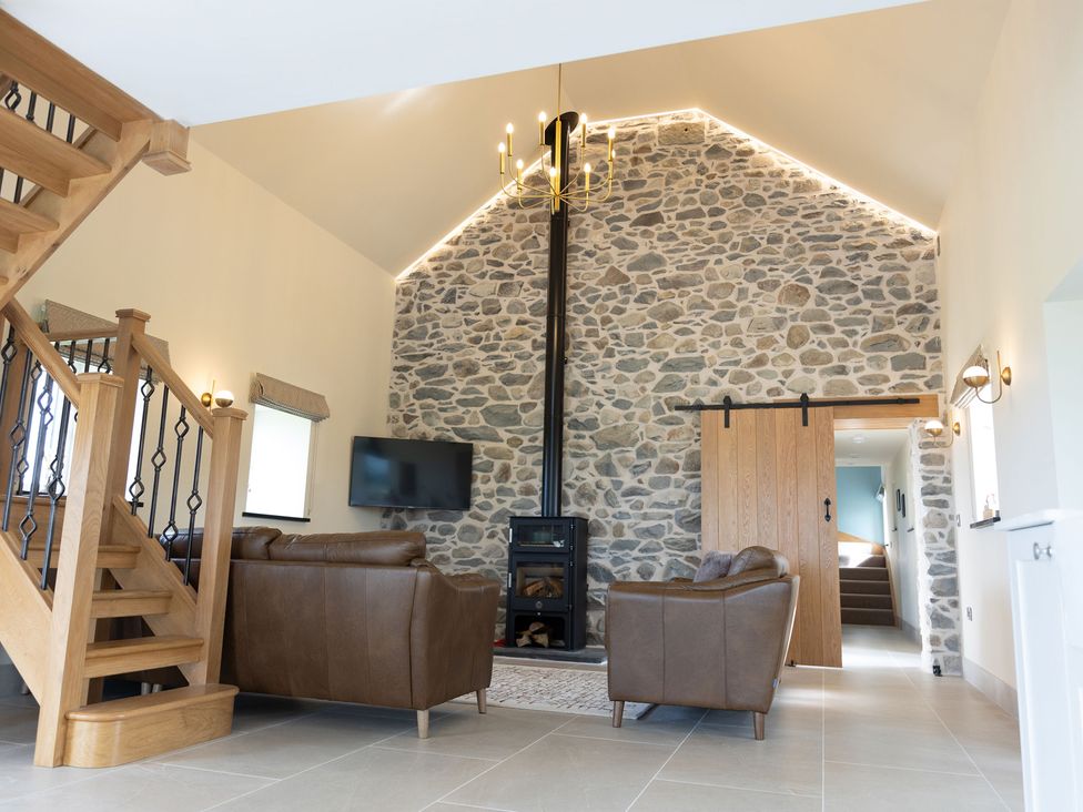 A living room with a stone wall and a television at Golygfa Cwrt near Bontgoch and Penrhyncoch
