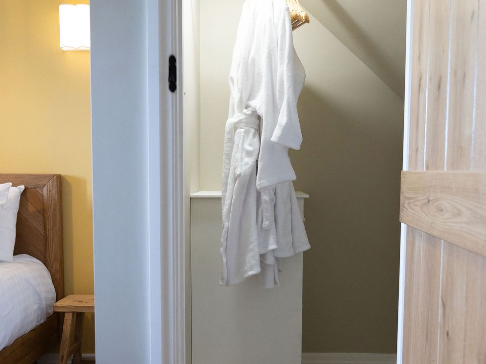 A robe hanging in a bedroom near a bed and nightstand at Golygfa Cwrt near Bontgoch and Penrhyncoch