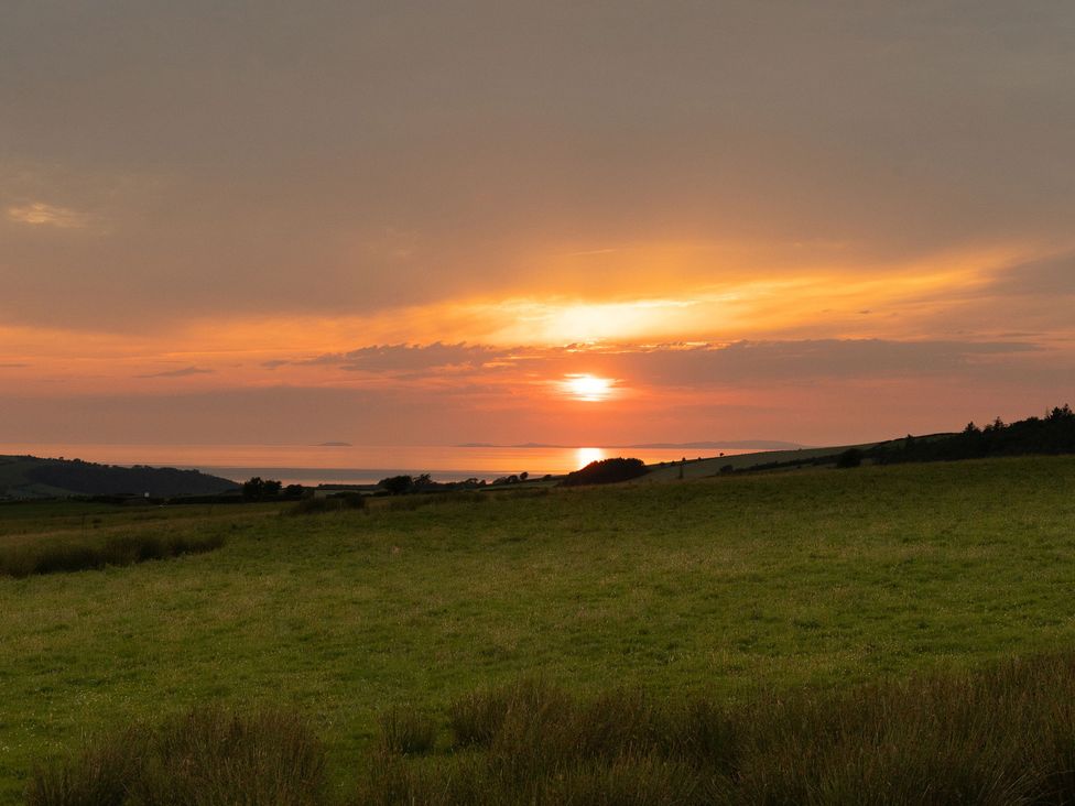 A sunset over a field and water at Golygfa Cwrt near Bontgoch and Penrhyncoch