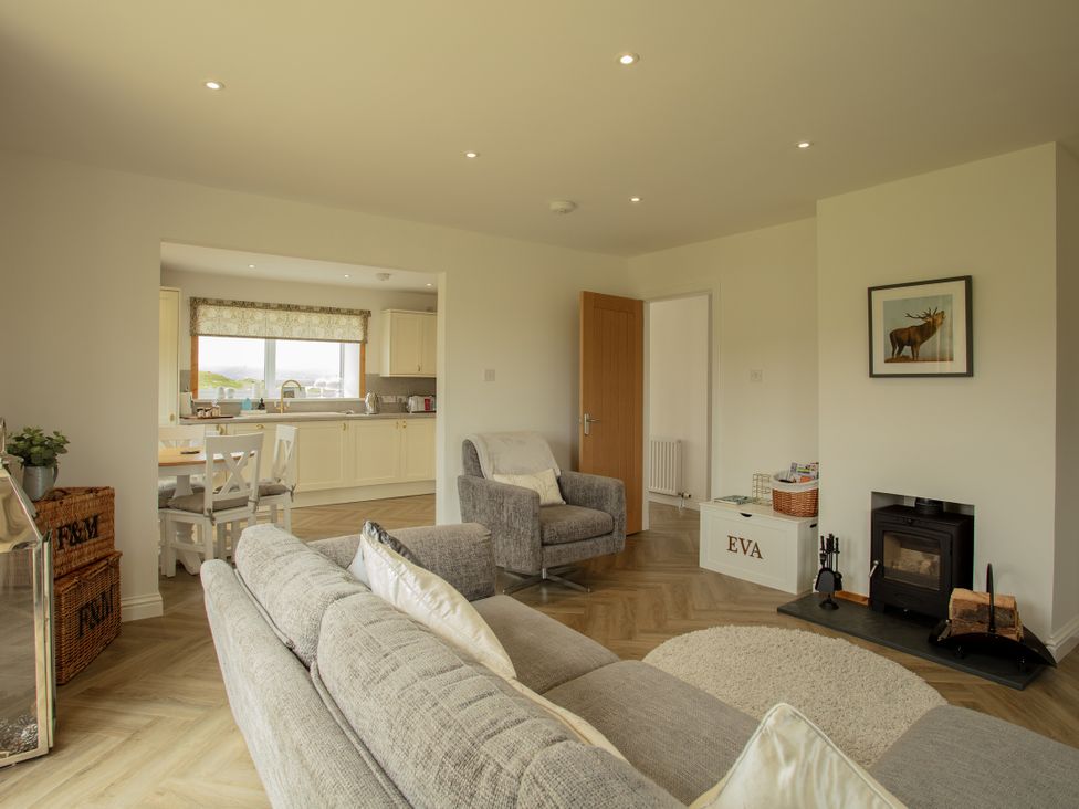 A living room with a fireplace and dining area at Taigh Eva near Lochmaddy