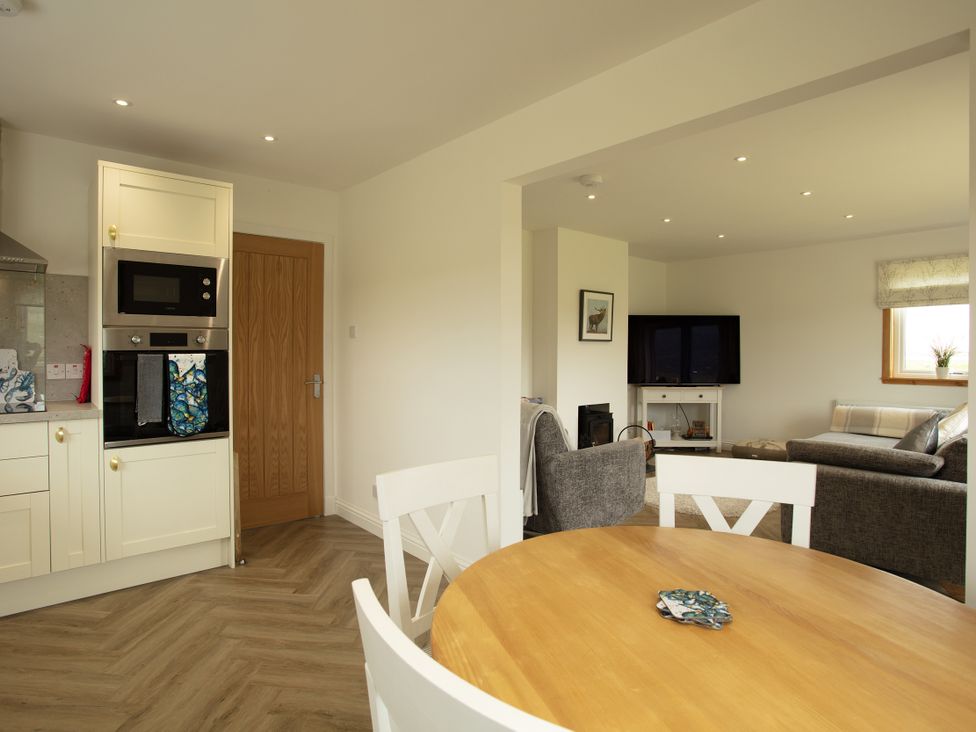 A kitchen area with a table and chairs and a living room view at Taigh Eva near Lochmaddy
