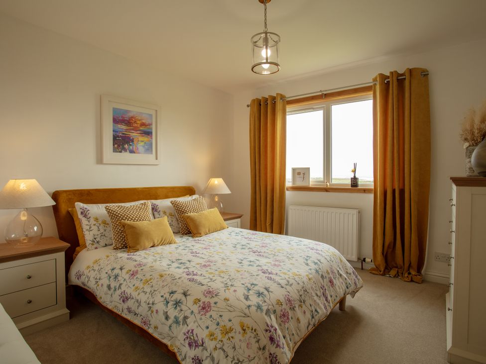 A bedroom with a bed and window at Taigh Eva near Lochmaddy