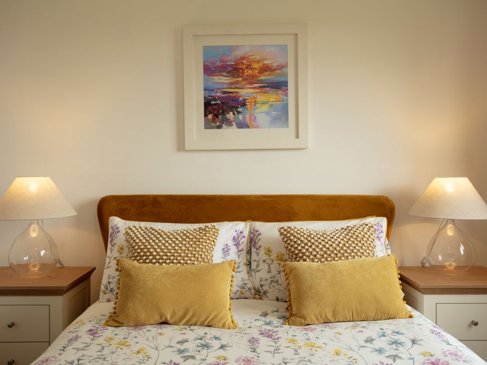 A bedroom featuring a bed with patterned bedding and lamps at Taigh Eva near Lochmaddy