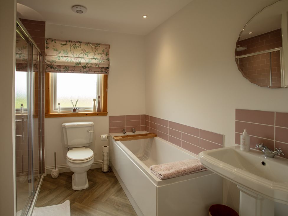 A bathroom with a toilet, bathtub, sink, and shower at Taigh Eva near Lochmaddy