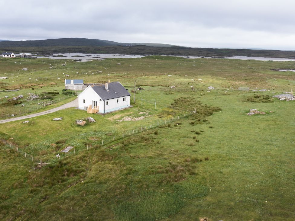 A house on grassy land with surrounding fence near Lochmaddy