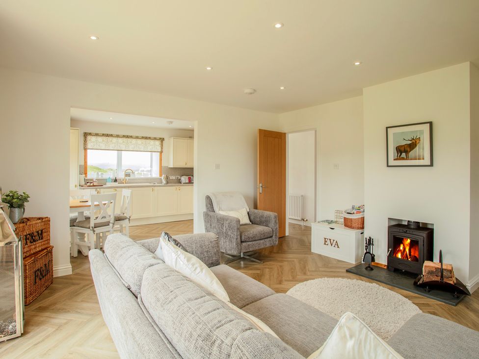 A living room with a fireplace and kitchen in Taigh Eva near Lochmaddy