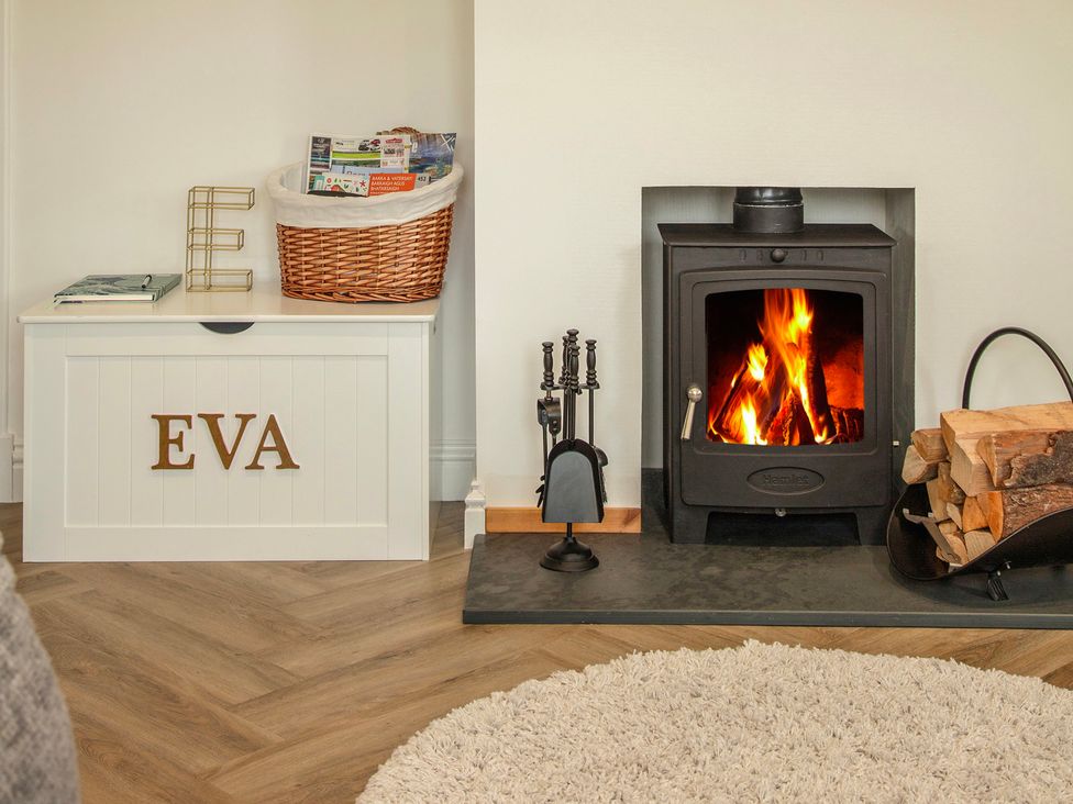 A living room with a fireplace and decorative storage at Taigh Eva near Lochmaddy