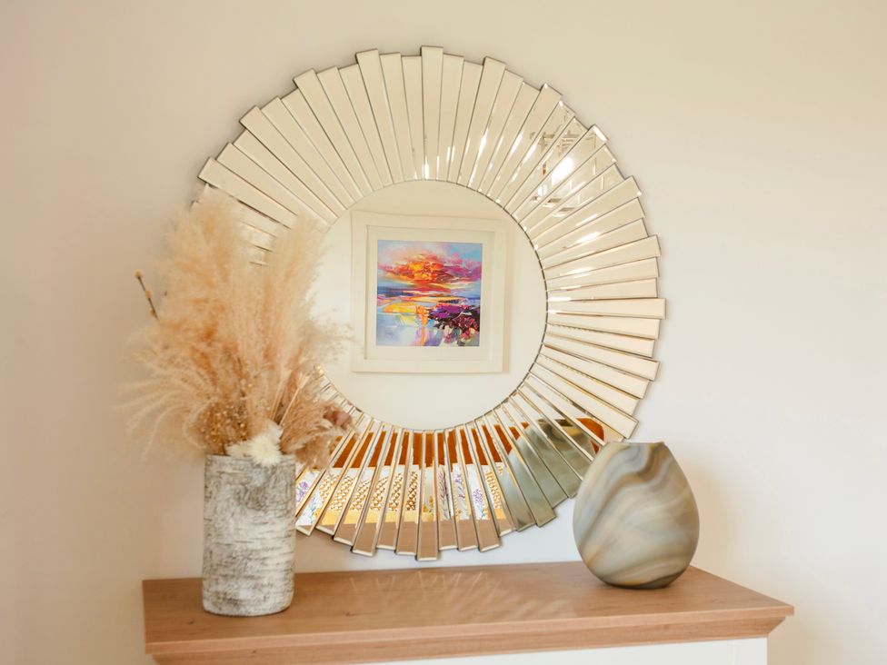 A mirror with artwork and vases on a shelf at Taigh Eva near Lochmaddy