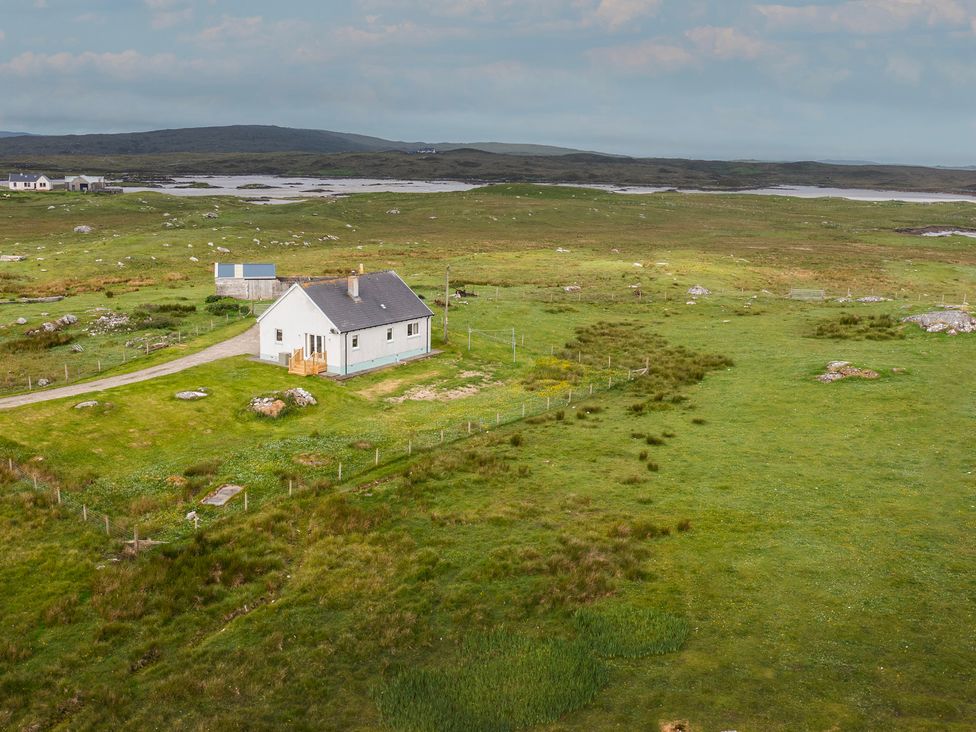 An outdoor view of a house surrounded by grass and rocks at Taigh Eva near Lochmaddy