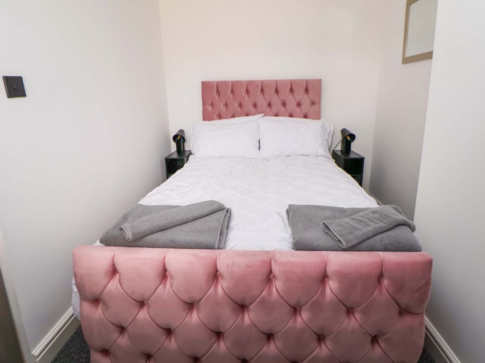 A bedroom with a pink bed and towels on the bed at 4 Willow Grove - Freehold Talacre