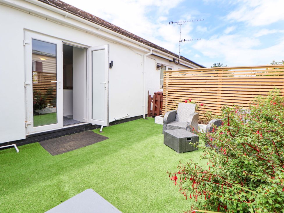 A green garden area with chairs and a table at 4 Willow Grove - Freehold Talacre