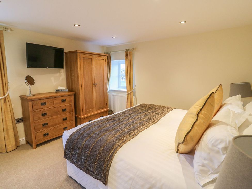 A bedroom with a television, wardrobe, and bed at Fogga Croft in Skipton