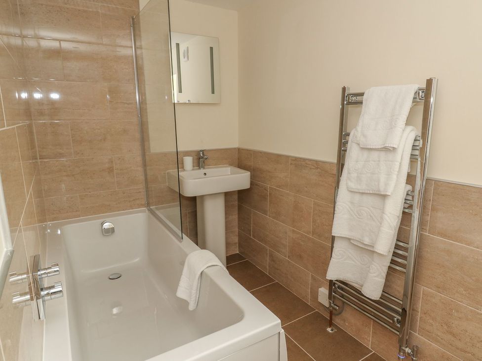 A bathroom with a bathtub, sink, and towel rail at Fogga Croft in Skipton