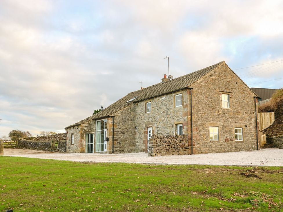 A stone house with windows and a gravel driveway at Fogga Croft in Skipton