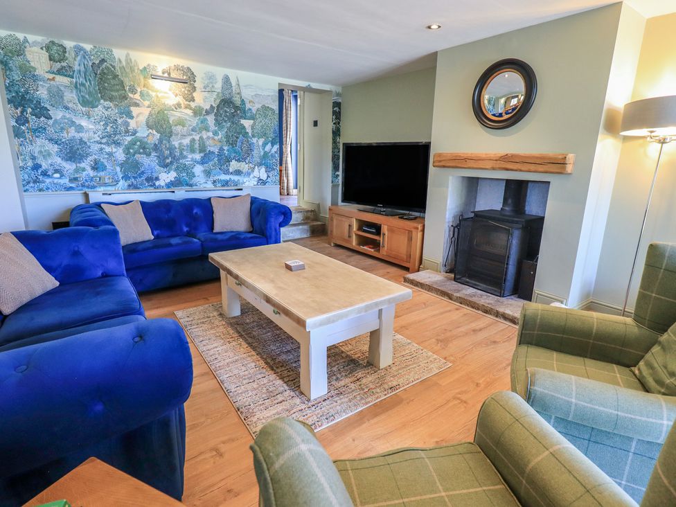 A living room with a blue sofa, coffee table, and fireplace at Fogga Croft in Gargrave