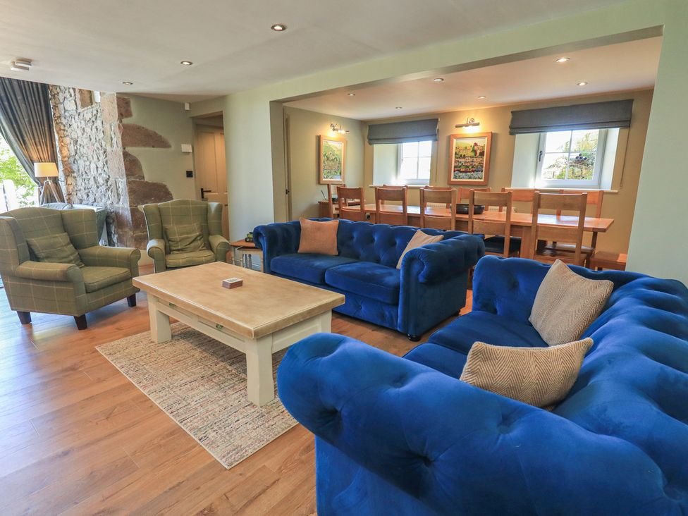 A living room with blue sofas, armchairs, and a dining area at Fogga Croft in Gargrave